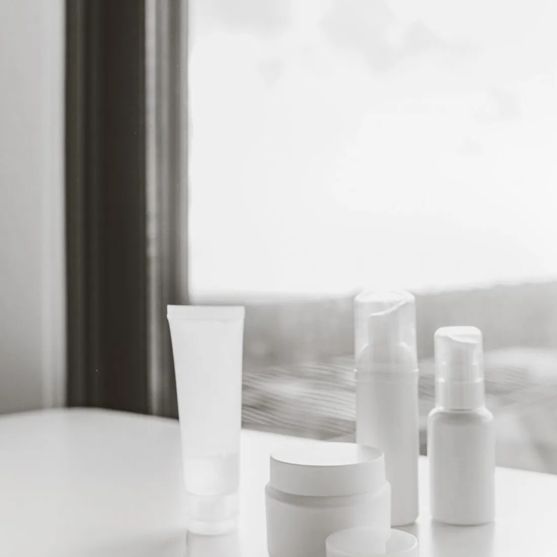 Envases blancos de cosmética junto a una ventana